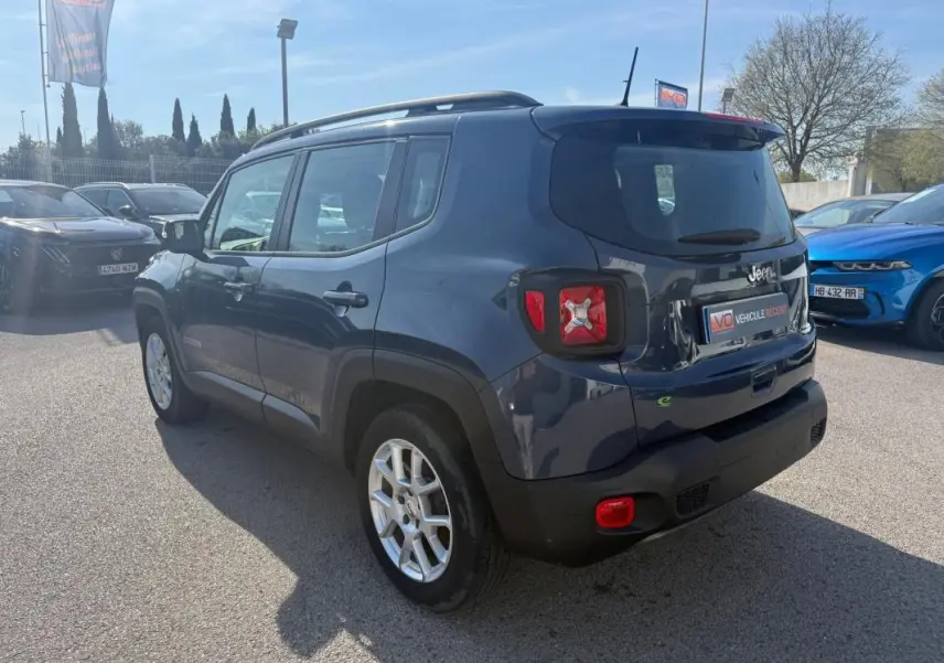 Jeep Renegade bleu vue 3/4 arrière droit, avec barres de toit et jantes alliage 17 pouces visibles.