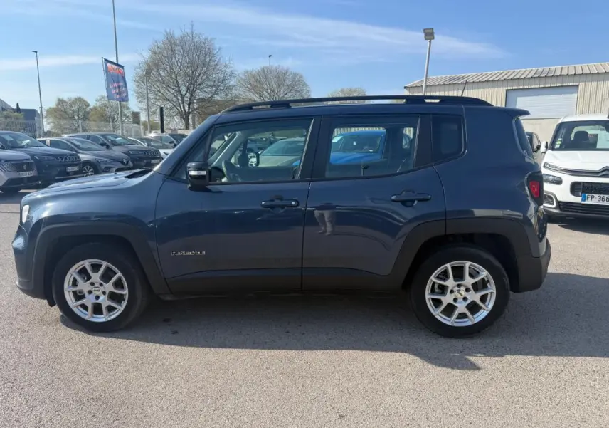 Vue de profil côté gauche d'une Jeep Renegade bleu 2023 avec jantes alliage 17 pouces et barres de toit noires.