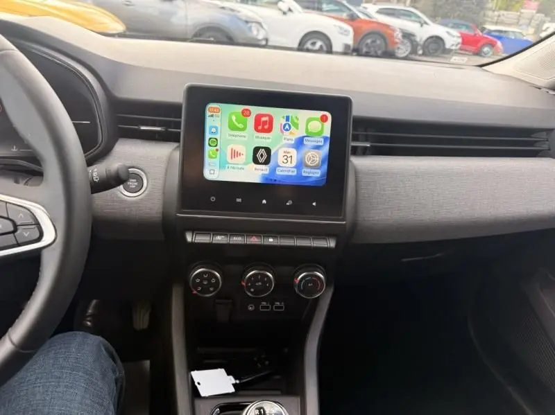 Vue intérieure de la Renault Clio V 1.5 DCI 100 Evolution 2025, tableau de bord avec écran tactile et volant partiel visible.