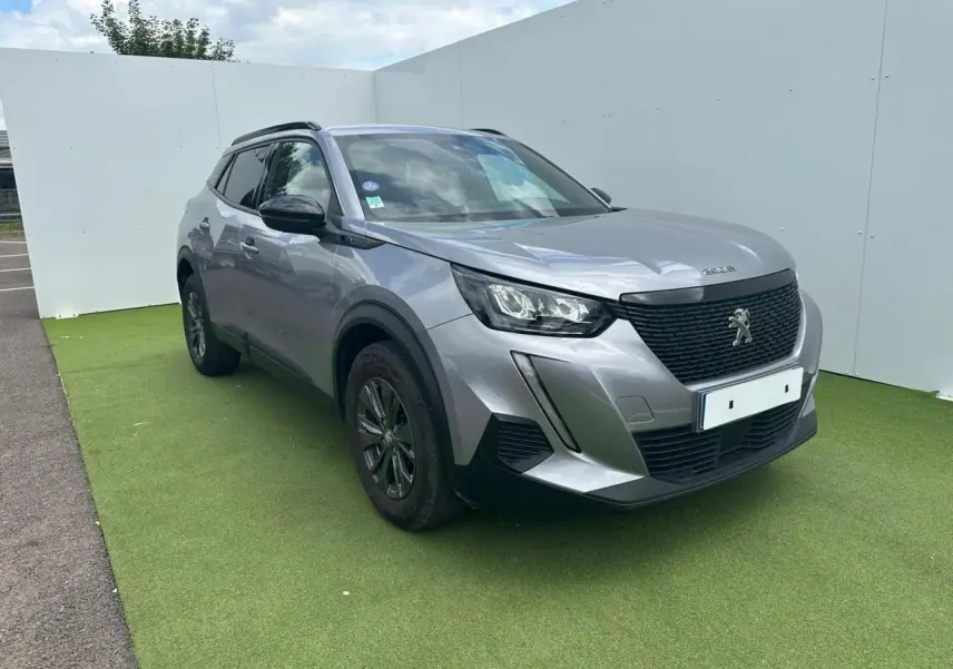 Peugeot 2008 gris clair en 3/4 avant droit, avec calandre noire et jantes alliage 16 pouces anthracite.