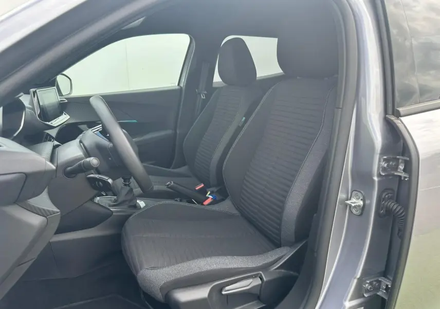 Intérieur avant de la Peugeot 2008 gris clair 2022, sièges tissu noir, volant compact et écran tactile visible côté conducteur.