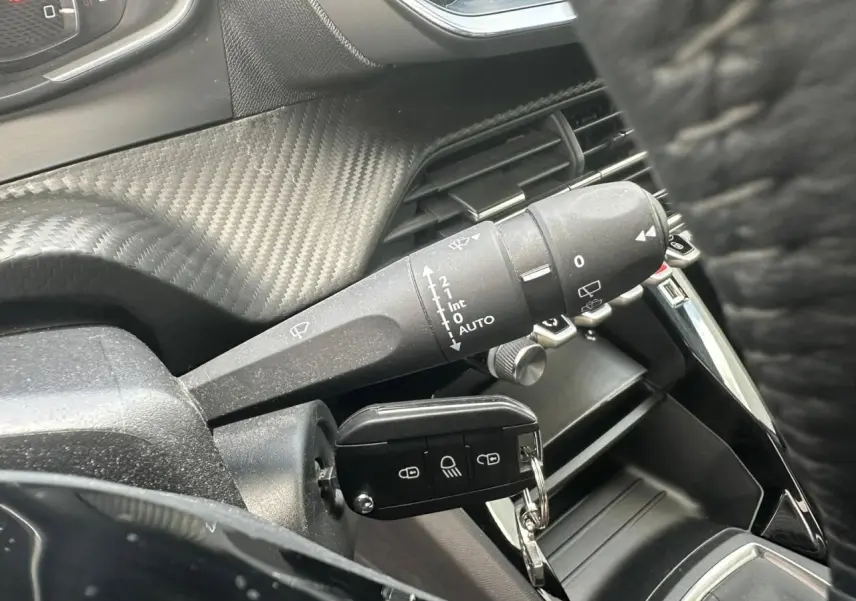Gros plan sur la commande d'essuie-glace et la clé insérée dans le contacteur d'une Peugeot 2008 gris clair.