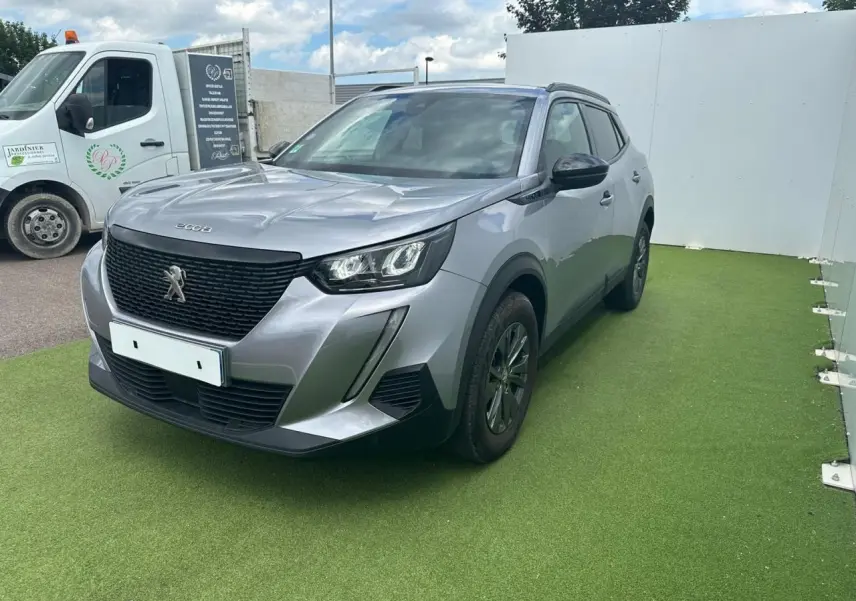 Peugeot 2008 gris clair en 3/4 avant droit, avec calandre noire et feux LED distinctifs.