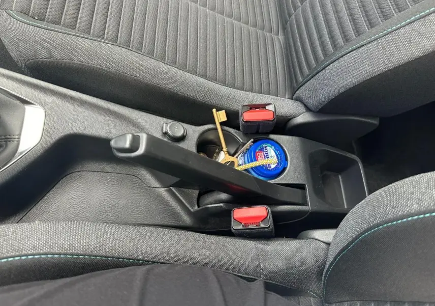 Gros plan sur la console centrale et frein à main d'un Peugeot 2008 II, sièges gris clair avec surpiqûres bleues.