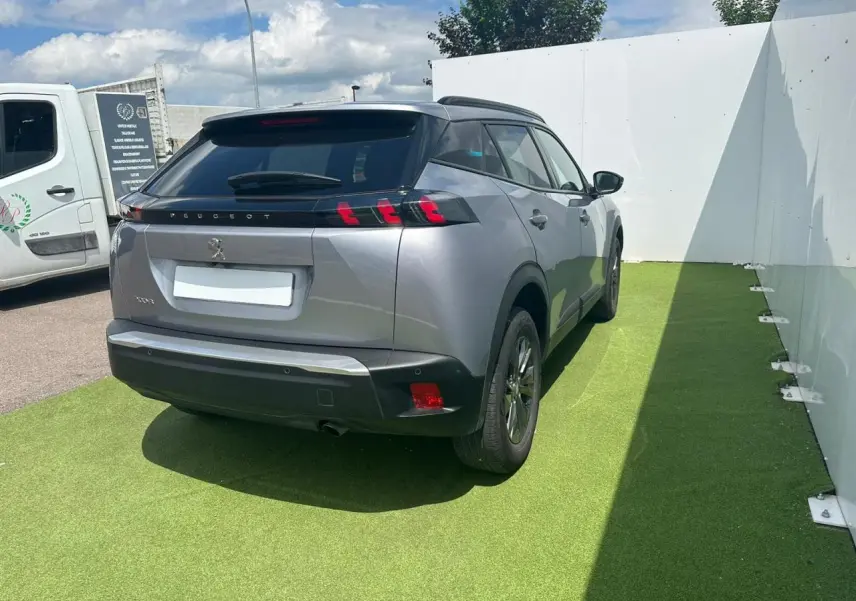 Vue 3/4 arrière droite d'un Peugeot 2008 gris clair avec feux arrière à trois griffes et toit noir brillant.