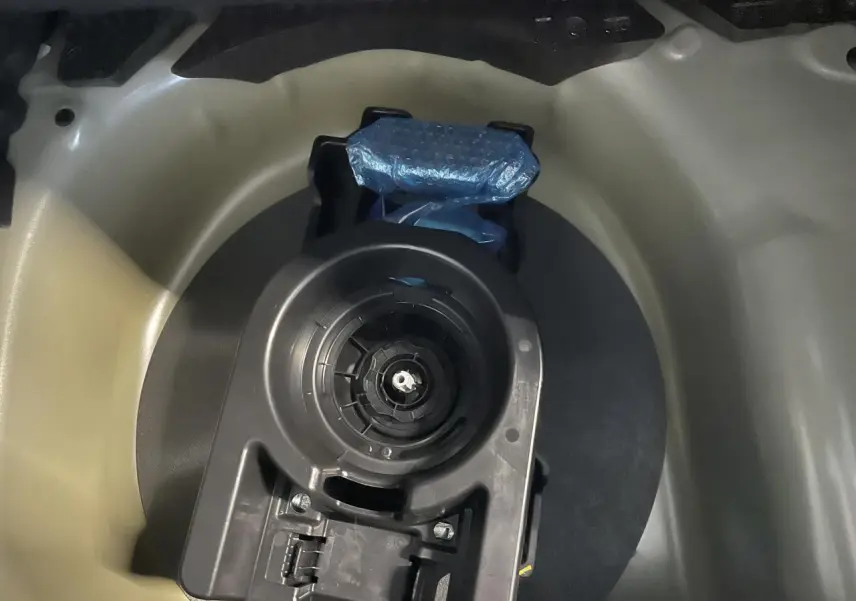 Gros plan sur le logement de la roue de secours dans le coffre d'une Peugeot 208 gris clair 2024.