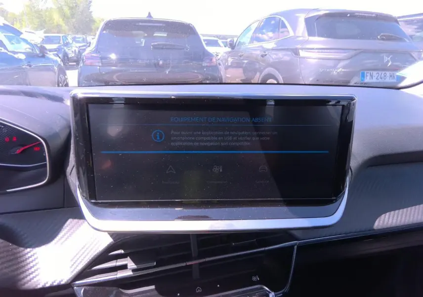 Vue intérieure du tableau de bord de la Peugeot 208 2024 avec écran tactile central et finitions carbone.