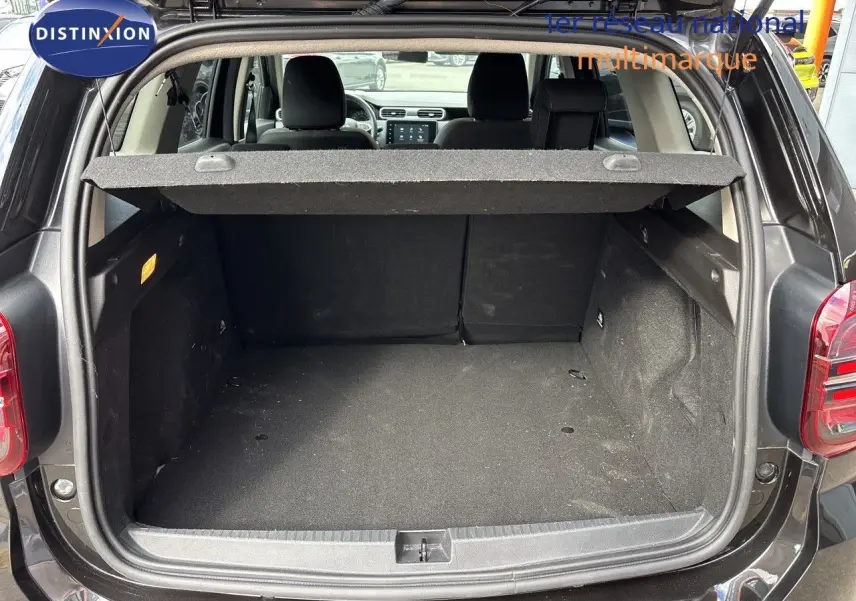 Coffre ouvert vu de l'arrière d'un Dacia Duster noir 2024, montrant l'espace de chargement vide et la plage arrière relevée.