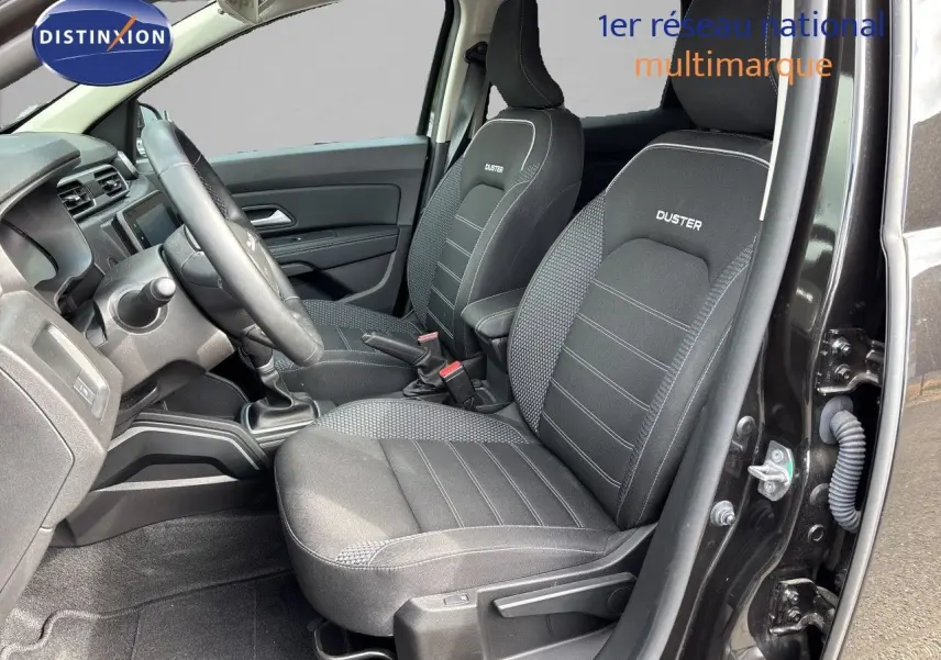 Vue intérieure côté conducteur du Dacia Duster noir 2024, sièges tissu noir avec logo Duster brodé.