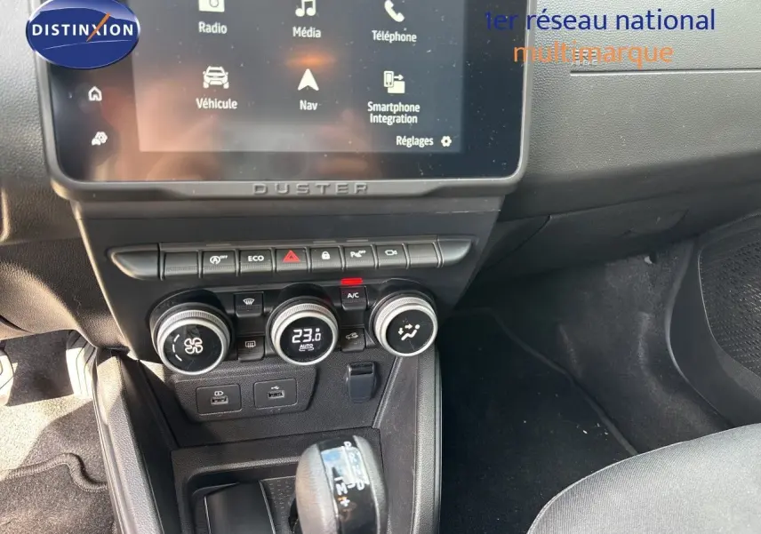 Vue intérieure centrée sur la console centrale du Dacia Duster noir 2024, avec écran tactile et commandes climatisation.