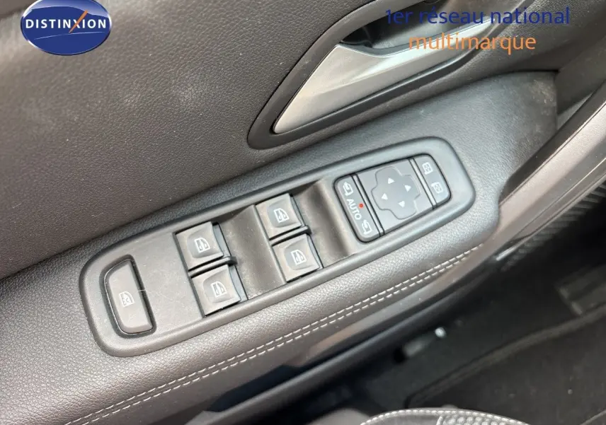 Gros plan sur les commandes des vitres électriques côté conducteur du Dacia Duster Journey noir, avec surpiqûres blanches visibles.