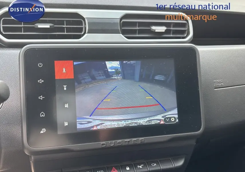 Écran tactile central du Dacia Duster noir 2024 montrant la caméra de recul avec lignes de guidage colorées.