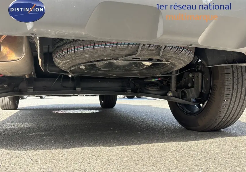 Vue en contre-plongée sous l’arrière du Dacia Duster noir 2024, montrant la roue de secours et le train arrière.