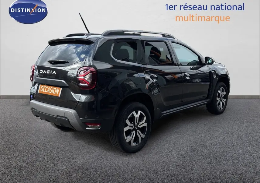Dacia Duster noir en 3/4 arrière droit, SUV compact avec jantes bi-ton et toit avec barres de toit.