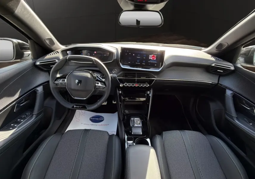 Intérieur noir du Peugeot 2008 Hybrid 145 GT vu de face, volant cuir multifonctions et écran tactile central.