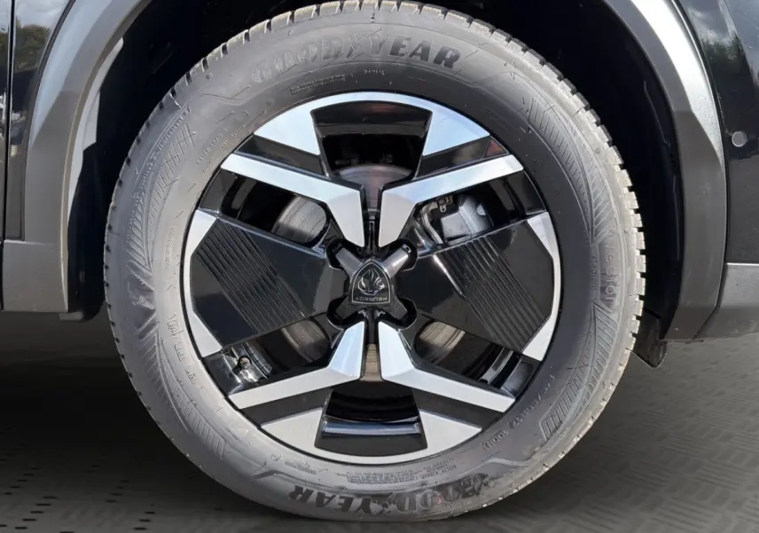 Gros plan sur la roue avant droite noire du Peugeot 2008 Hybrid 145 e-DCS6 GT avec jante alu bicolore et pneu Goodyear.