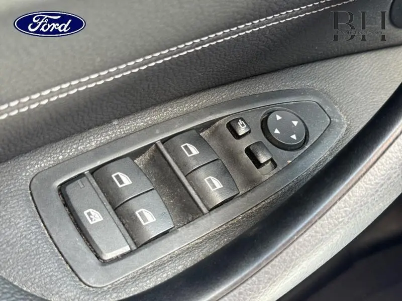 Gros plan sur les commandes électriques des vitres et rétroviseurs sur la porte intérieure d'un BMW X1 Saphirschwarz.