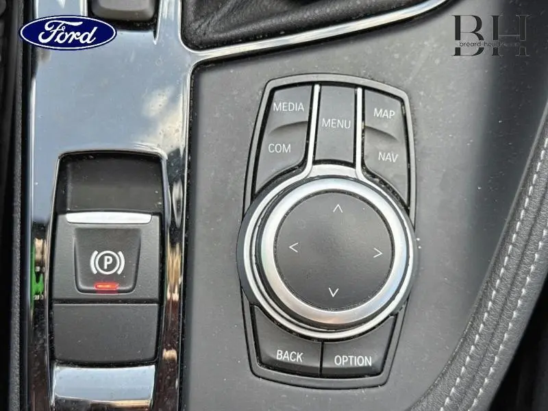 Gros plan sur la molette de commande multimédia et le frein à main électronique dans l'habitacle d'une BMW X1 Saphirschwarz.