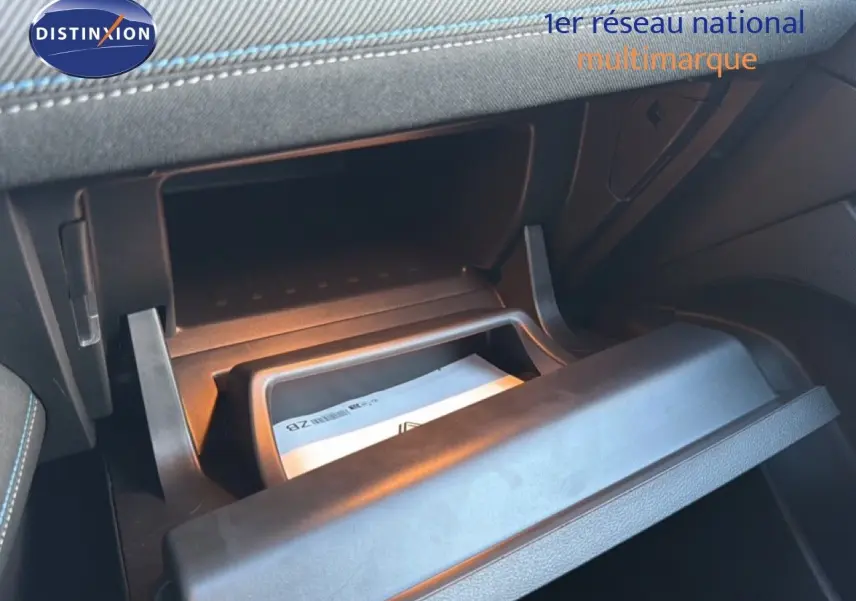 Gros plan sur la boîte à gants ouverte du Renault Captur 2025, intérieur noir avec surpiqûres bleues visibles.