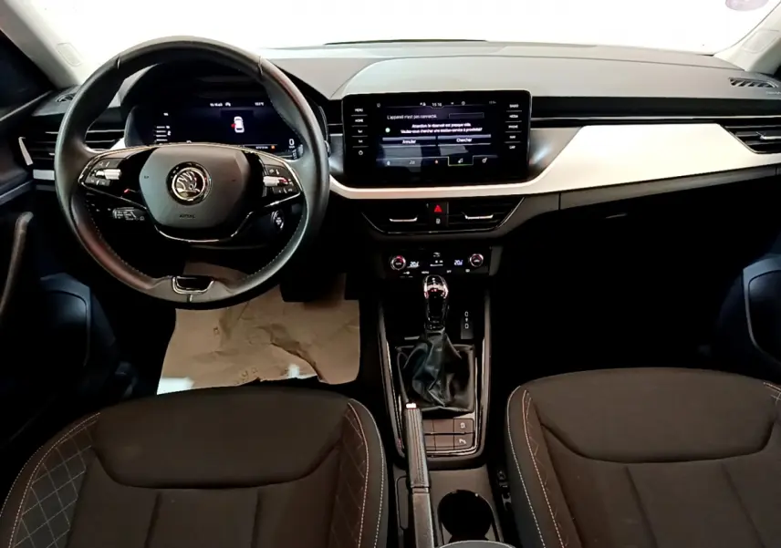 Intérieur de la Skoda Kamiq 2022 vue de face, tableau de bord moderne avec écran tactile et volant cuir noir.