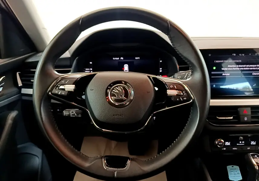 Volant cuir noir avec logo Skoda au centre, tableau de bord numérique et écran tactile dans l'habitacle du Kamiq gris clair.