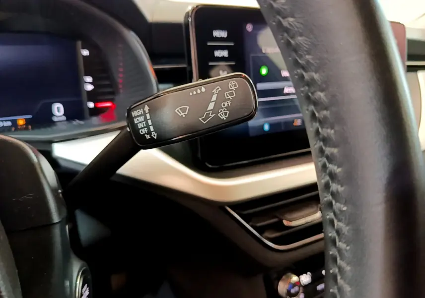 Gros plan sur la commande d’essuie-glace du tableau de bord noir et beige du Skoda Kamiq 2022, avec écran tactile en arrière-plan.