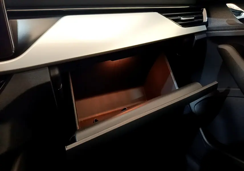 Vue intérieure du coffre à gants ouvert avec éclairage intérieur, tableau de bord gris clair du Skoda Kamiq 2022.