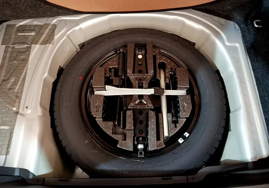 Roue de secours galette noire avec kit de réparation dans le coffre gris clair d'une Skoda Kamiq 2022.