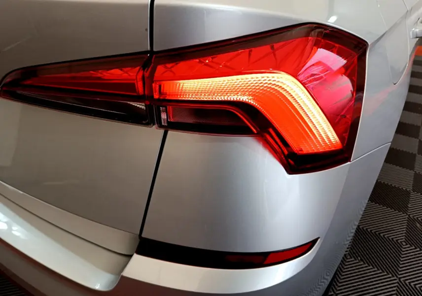 Gros plan sur le feu arrière droit rouge d’un Skoda Kamiq gris clair 2022, avec détails du coffre et pare-chocs.
