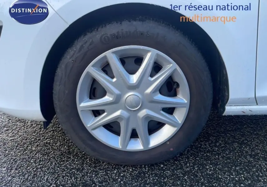 Gros plan sur la roue avant droite avec jante classique 15 pouces d'une Ford Fiesta blanche 2020.