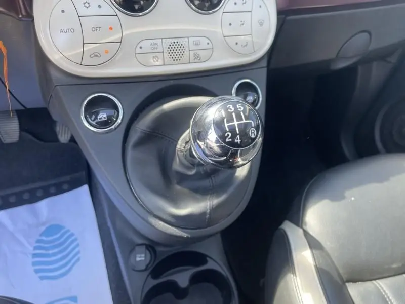 Gros plan sur la boîte manuelle de la Fiat 500 gris foncé, version 1.2 69 cv Club, avec console centrale et sièges visibles.