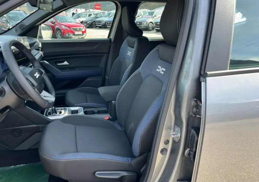 Vue intérieure côté conducteur du Dacia Bigster gris schiste 2026, sièges tissu bi-matière avec logo brodé.