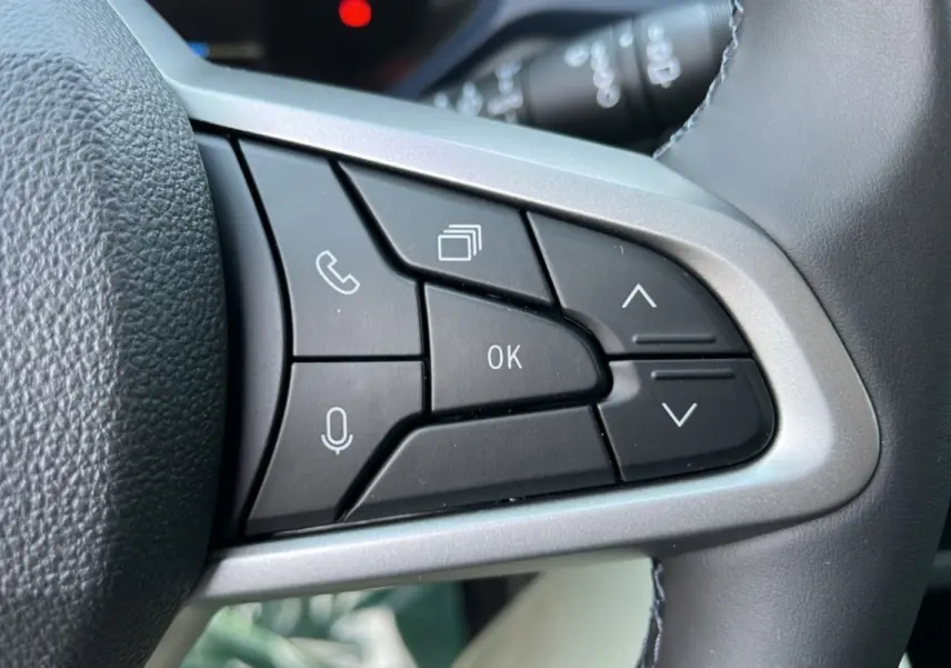 Gros plan sur les commandes multifonctions noires du volant cuir du Dacia Bigster Hybrid 155 Expression Plus.