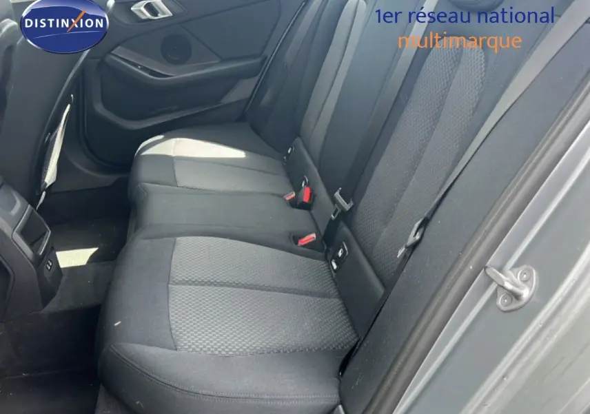Vue intérieure côté arrière droit de la BMW Série 1 116i 2022 avec sièges tissu gris et portières assorties.