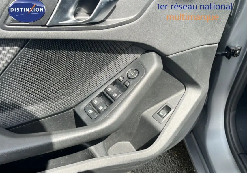 Gros plan sur la porte avant gauche grise d'une BMW Série 1 116i, montrant les commandes de vitres et rétroviseurs.