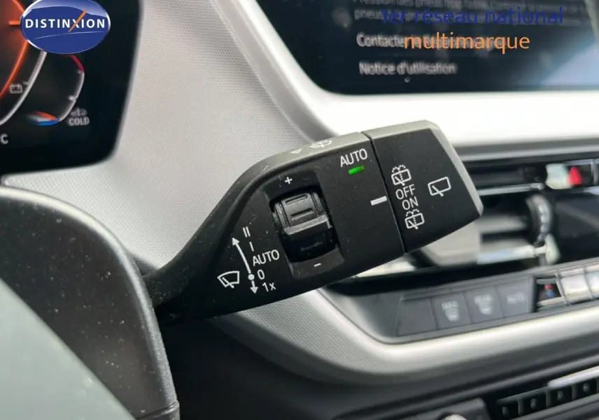 Gros plan sur la commande d’essuie-glace à gauche du volant dans l’habitacle gris et noir d’une BMW Série 1 116i 2022.