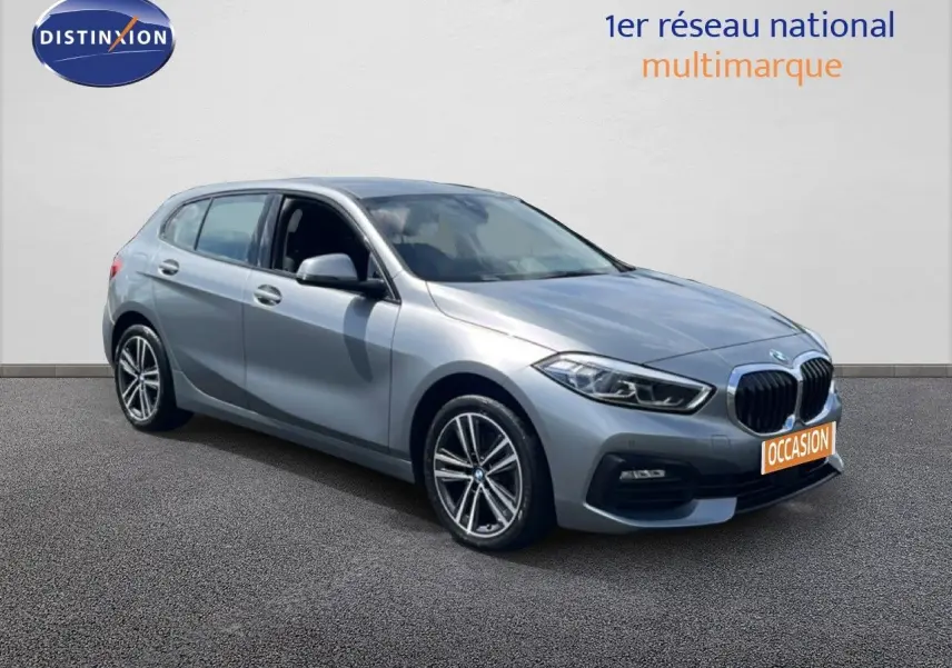BMW Série 1 116i 2022 en Frozen Pure Grey vue 3/4 avant droit avec calandre noire et jantes bi-ton.