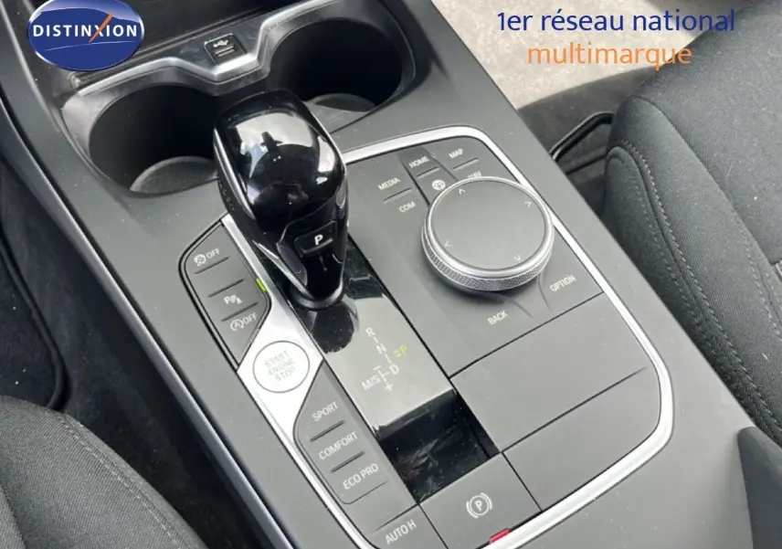 Gros plan sur la console centrale de la BMW Série 1 116i 2022, avec levier de vitesse noir brillant et commandes de mode de conduite.