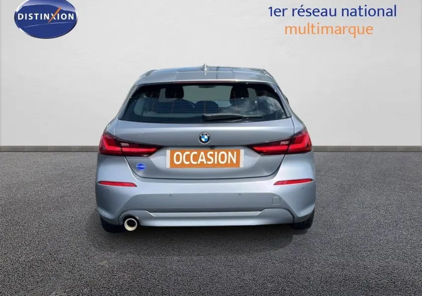 Vue arrière d'une BMW Série 1 116i 2022 en gris Frozen Pure Grey avec feux arrière LED et sortie d'échappement côté gauche.