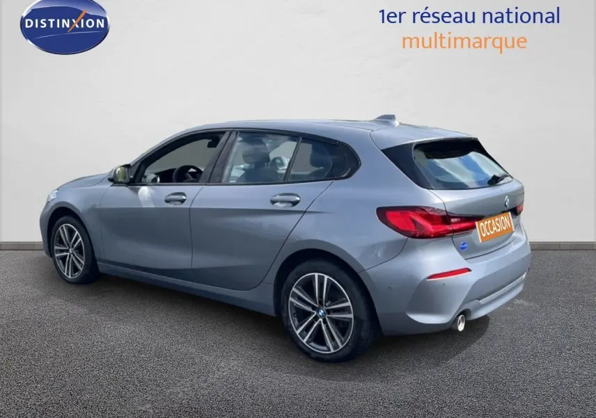 BMW Série 1 116i 2022 en Frozen Pure Grey, vue 3/4 arrière droit avec jantes bi-ton et feux LED distinctifs.
