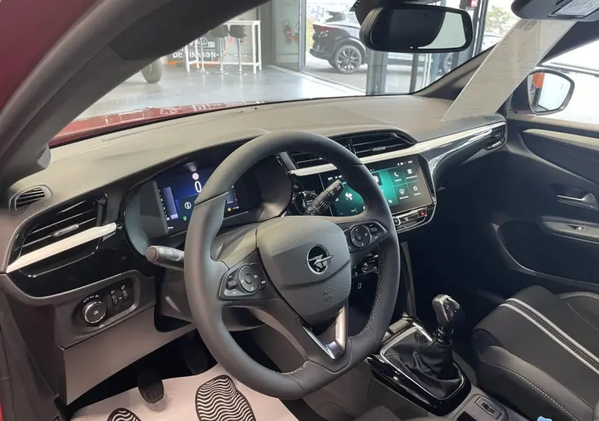 Vue intérieure côté conducteur de l’Opel Corsa rouge 2026, volant cuir, écran tactile 10 pouces et boîte manuelle.