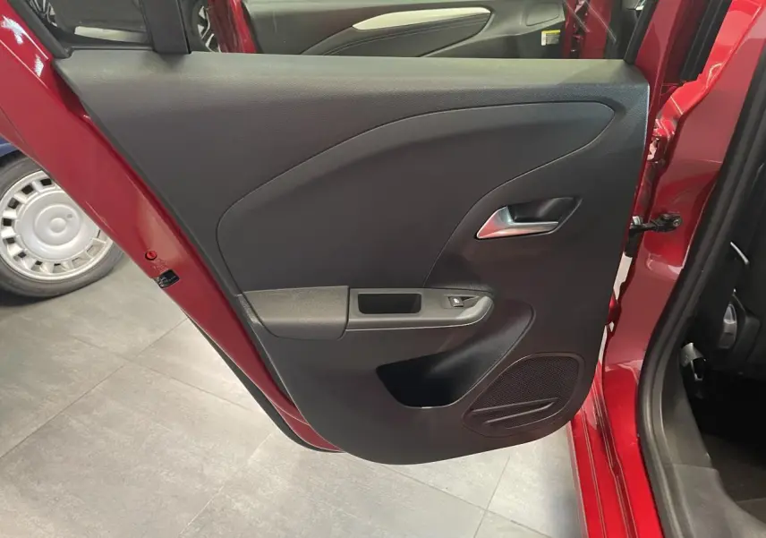 Vue rapprochée de la porte arrière gauche rouge d’une Opel Corsa 2026 avec panneau intérieur noir et poignée argentée.
