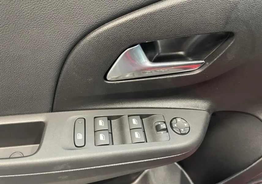 Détail de la porte côté conducteur de l’Opel Corsa rouge montrant les commandes électriques des vitres et rétroviseurs.