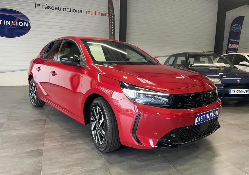 Opel Corsa rouge vue 3/4 avant droit en intérieur avec calandre noire et jantes alliage diamantées.