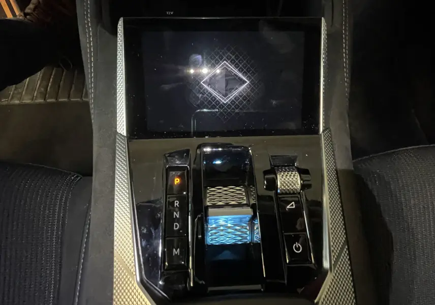 Vue rapprochée de la console centrale du DS4 2024, avec levier de vitesse lumineux et sellerie tissu tressé basalte visible.