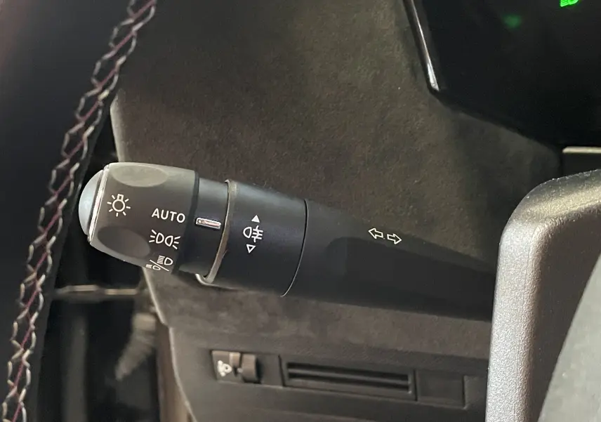 Gros plan sur la manette de clignotants et feux du DS4 gris platinium, avec finition Alcantara visible en arrière-plan.