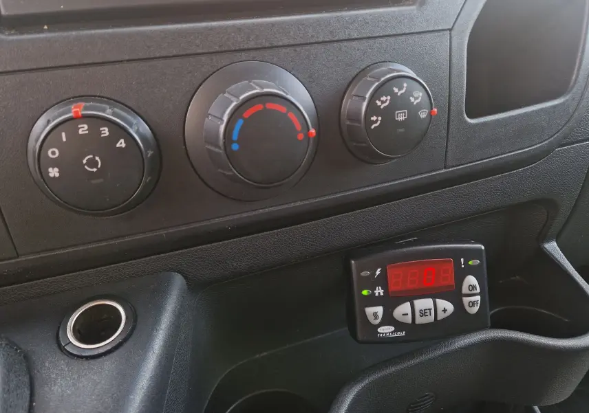 Gros plan sur la console centrale noire du Renault Master Plancher Cabine blanc, avec commandes clim et régulateur frigo digital.