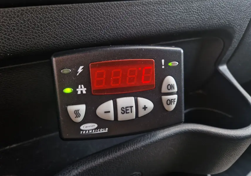 Gros plan sur le panneau de contrôle du groupe frigo Carrier Transicold avec écran rouge dans l'habitacle noir.