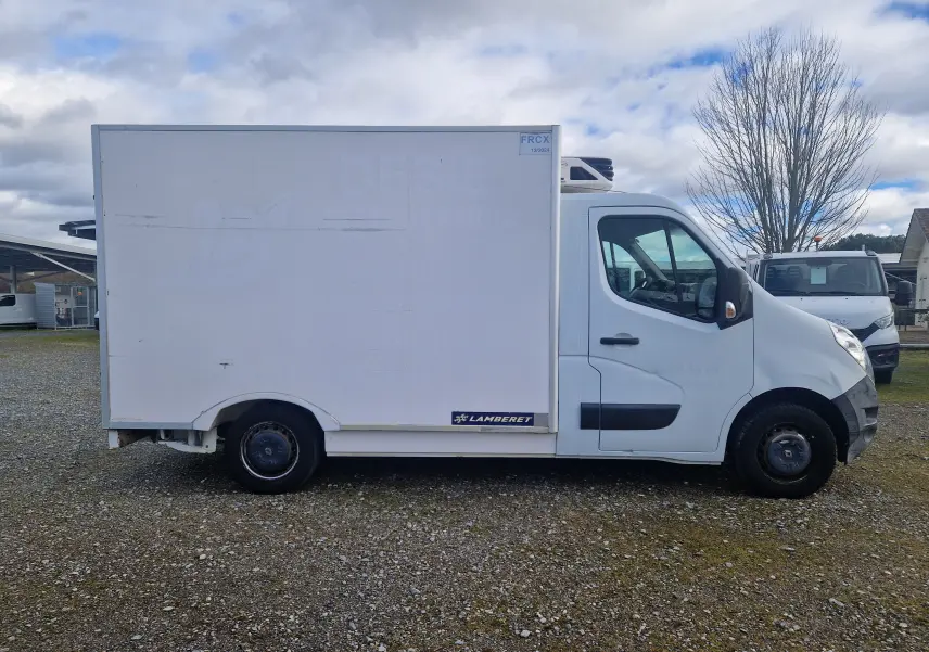 Vue de profil côté droit d’un Renault Master Plancher Cabine blanc avec cellule frigorifique Lamberet sur un sol gravillonné.