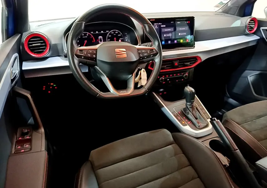 Intérieur du SEAT Arona bleu, vue depuis le siège conducteur sur le volant, tableau de bord et écran tactile central.